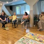 Uczestnicy warsztatów. Jedna z uczestniczek przy wykorzystaniu opracowanej przez siebie maski prezentuje swoją osobę.